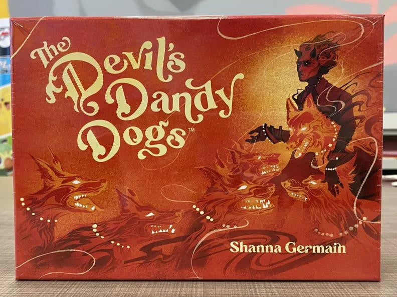 The Devils Dandy Dogs board game box showing a devil and three fiery ghost dogs for a narrative roleplaying game.