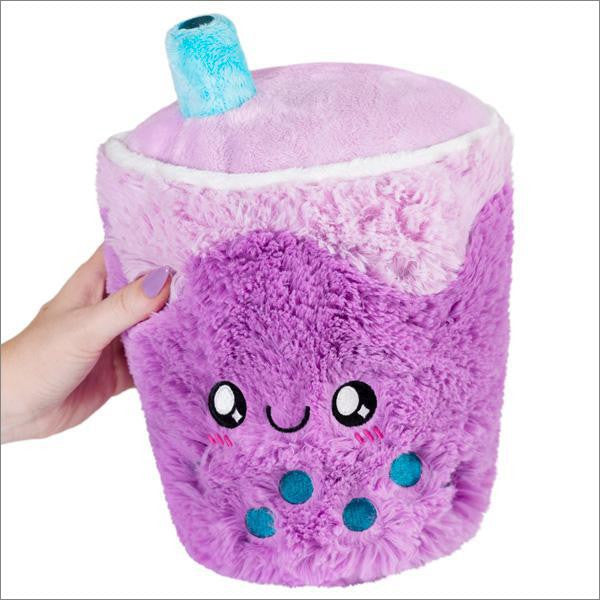 Bubble Tea 11 Mini Squishable, a plush purple bubble tea cup with a smiling face, held in one hand.