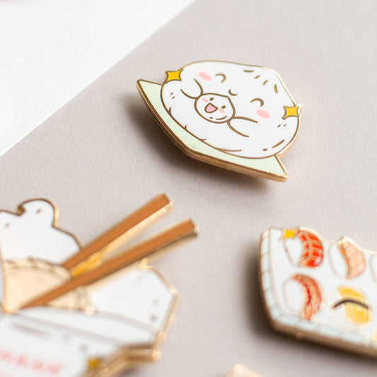 Big and Little Baos Enamel Pin with bao designs on a neutral background, viewed from above.