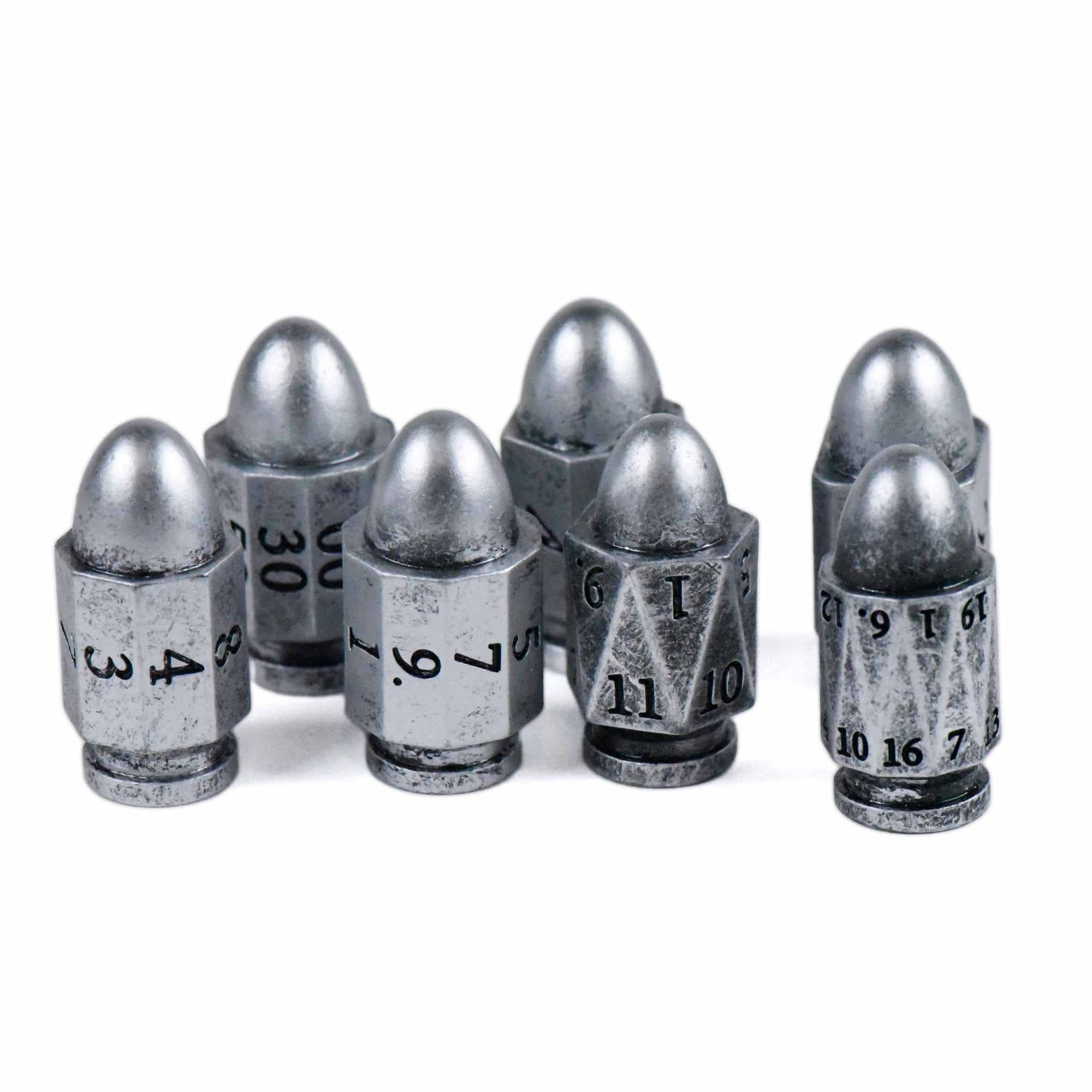 7-piece metallic polyhedral dice set shaped like bullets, each engraved for tabletop gaming.