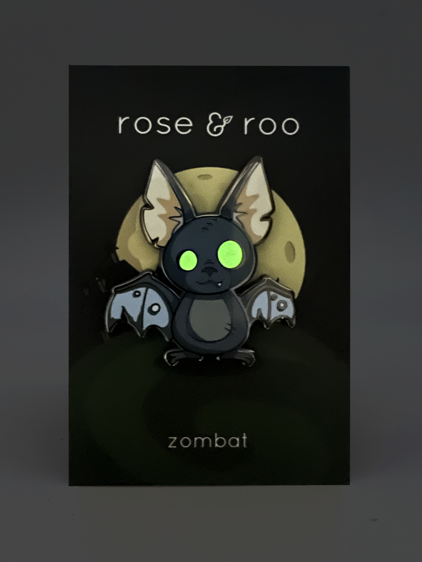 Zombat Bat Enamel Pin, glow-in-the-dark variant, on a card labeled rose & roo and zombat.