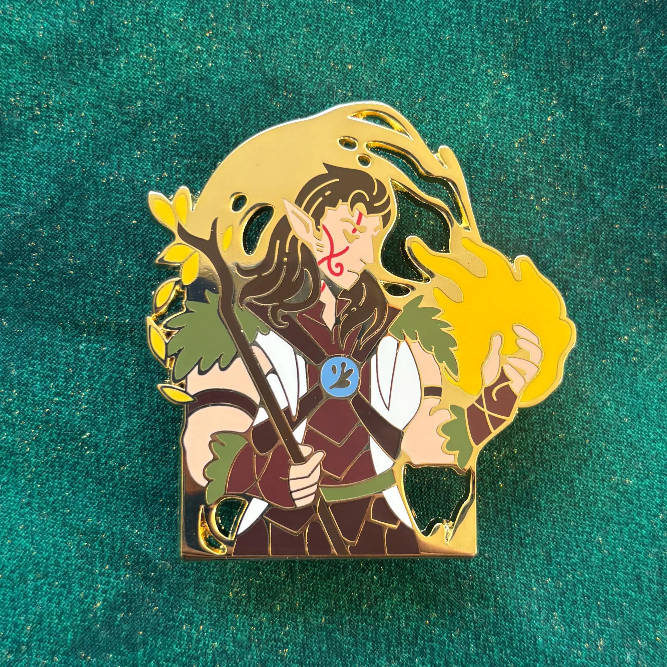 Halsin enamel pin featuring an elf mage holding a staff and conjuring yellow magic.