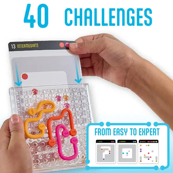 A hand sliding an intermediate card into a Noodle Maze grid with movable colored U-shaped pieces.