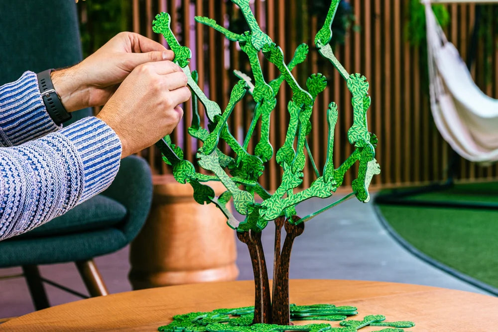 Offshoots green wooden tree stacking game with patterned leaves being assembled on a table.