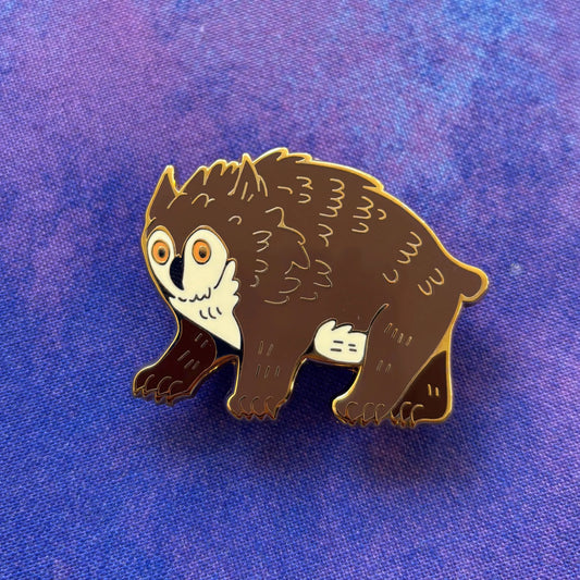 Owlbear enamel pin with vibrant colors on a purple textured background.
