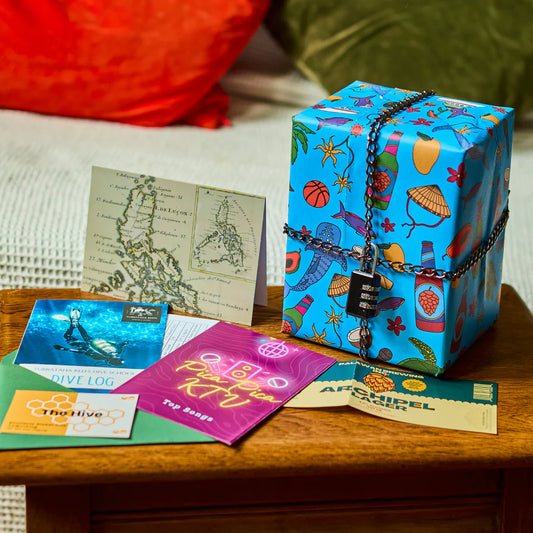 Padlockd The Philippines blue gift box with travel-themed designs, shown with postcards and travel documents.