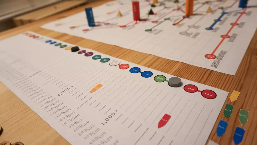 Tokyo Metro board game with colored pieces and score sheets displayed on a wooden table.