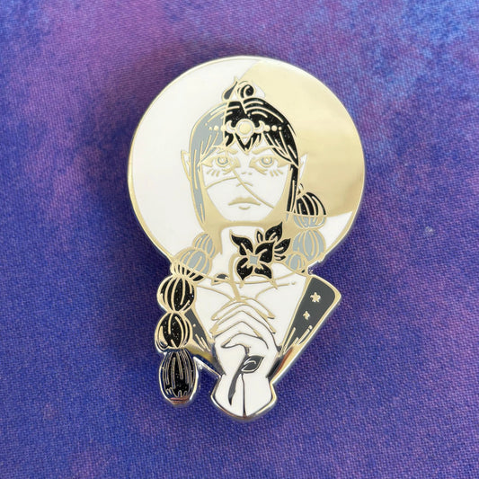 Gold enamel pin of an elf with braided hair, pointed ears, and a flower on purple enamel.