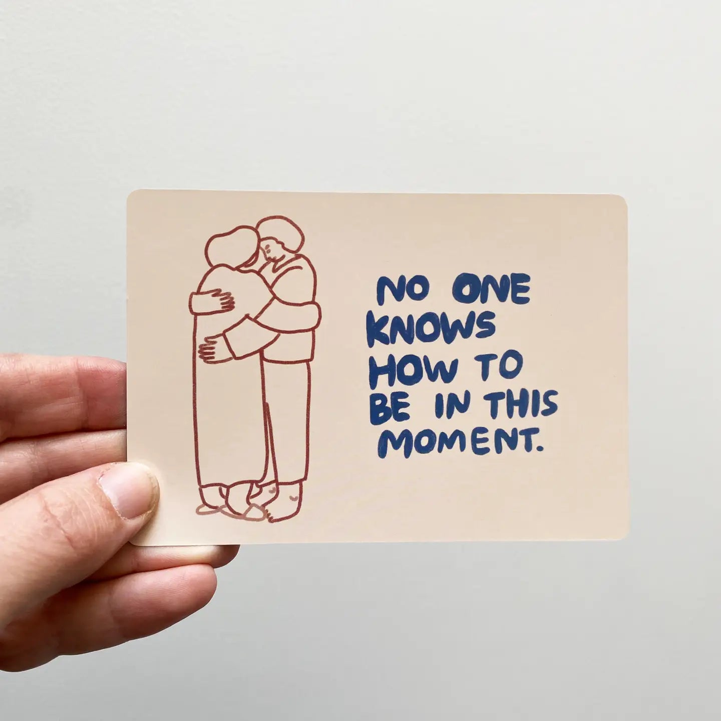 Sitting With Sadness Deck card held in hand, displaying two people hugging and the text: Coping with loss is hard.