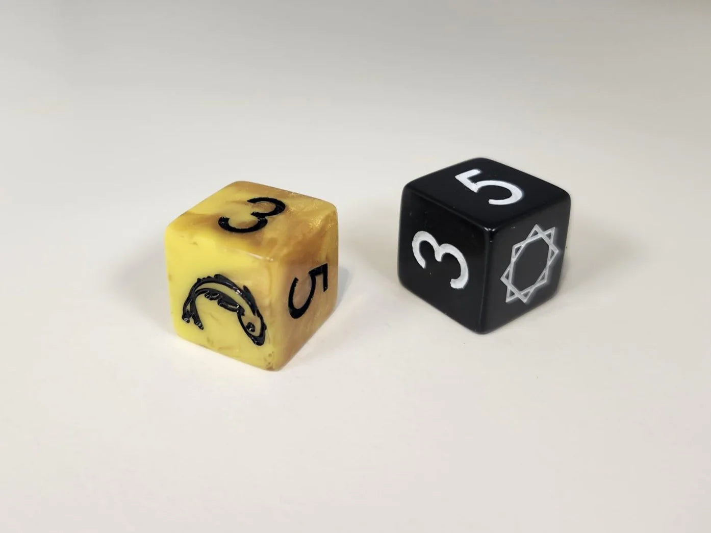 Gold and black six-sided dice, each showing 3 and 5, for The Real Thing RPG.